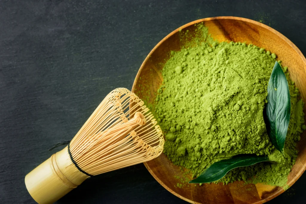 Matcha powder with two full matcha leave in a wooden bowl with a bamboo mixer | RW Golden Matcha