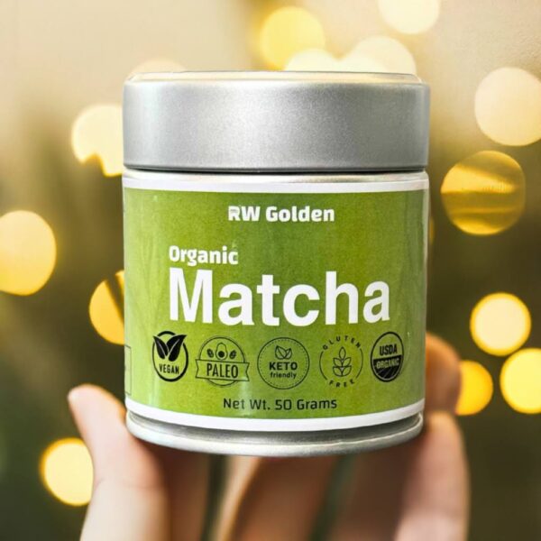 A close up shot of a person holding a tin of RW Golden Organic Matcha