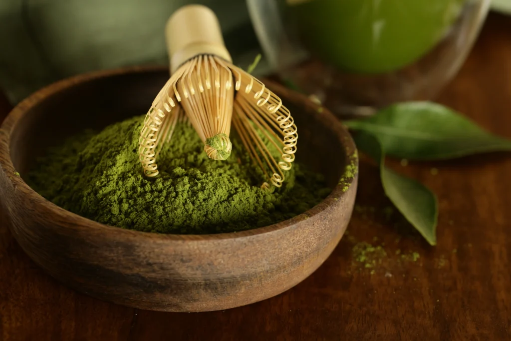 Matcha powder in a wooden bowl with a bamboo whisk | RW Golden Matcha